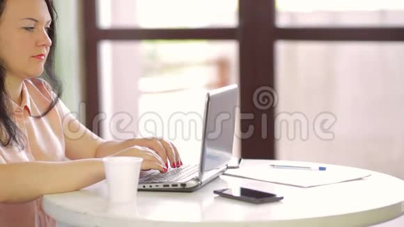 那个女人坐在咖啡馆里在笔记本电脑后面工作慢节奏视频的预览图