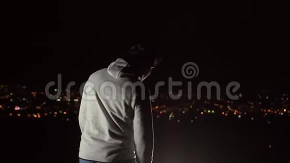 一个张开双臂的男人在夜晚看到城市景色慢悠悠视频的预览图