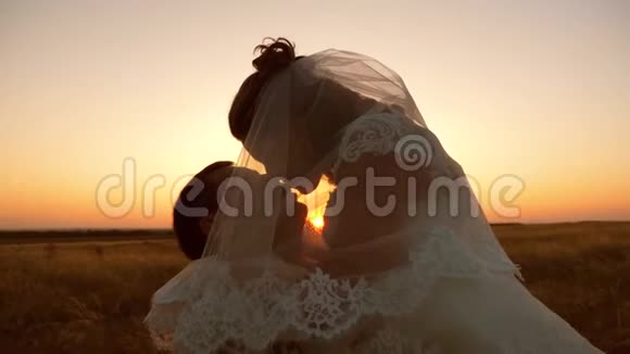 新娘和新郎在日落时亲吻和拥抱浪漫的情侣在日落时接吻幸福家庭的概念视频的预览图