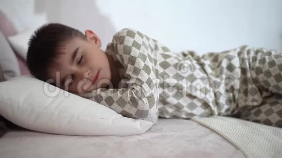 一个穿睡衣的小男孩睡在床上视频的预览图