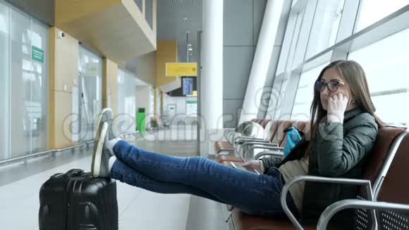 无聊的年轻女子正坐在大厅的机场等待她的航班视频的预览图