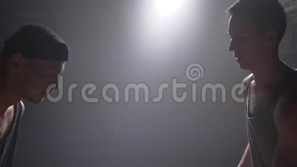 篮球运动员用烟雾和泛光灯阻挡另一名球员的球在健身房打球视频的预览图