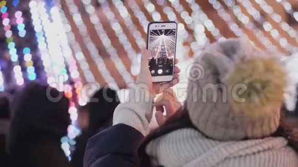 一位女士在智能手机上拍摄一棵城市圣诞树视频的预览图