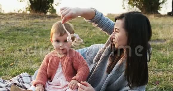 母亲和一个小女儿一起在城市公园野餐年轻的女人和小女孩在玩视频的预览图