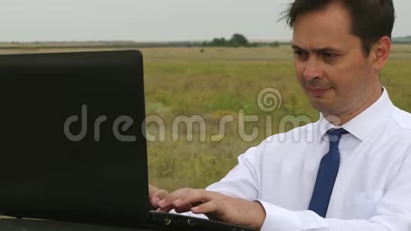 穿着白衬衫和领带的商人正在汽车车顶上的电脑上工作视频的预览图