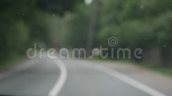 毒蛇清理汽车上的挡风玻璃在模糊的乡间道路上4k视频的预览图