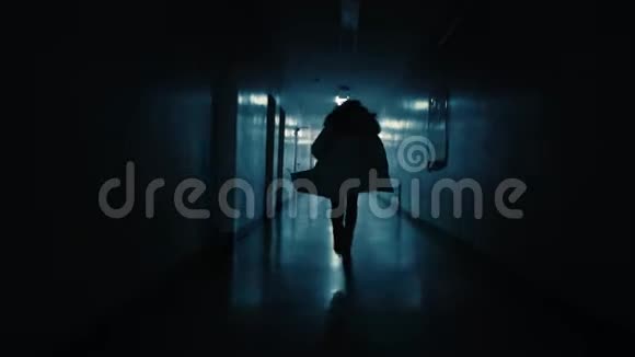 一个年轻的女人沿着黑暗的走廊从追求她的人身边逃跑视频的预览图