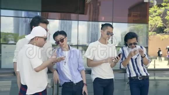 年轻的亚洲成年人在街上闲逛看手机视频的预览图