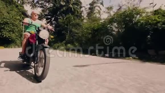 骑摩托车在热带森林景观道路上的老人一个骑摩托车的老人在摩托旅行视频的预览图