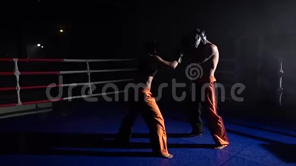 戴着头盔和拳击手套的男人和女孩在拳击场上打架慢动作视频的预览图