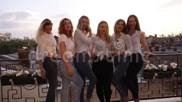 六个白种人女孩站在阳台上摆姿势拍照休闲服把女孩的腿收起来视频的预览图