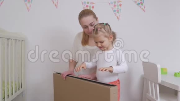 妈妈和女儿为一个孩子打开一个新买的大纸盒视频的预览图