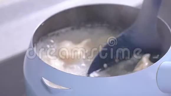在煤气炉上煮和煮美味的饺子放在淡蓝色的锅里厨房里有水很近生活方式视频的预览图