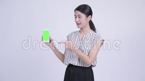快乐美丽的亚洲女商人展示电话和竖起大拇指视频的预览图