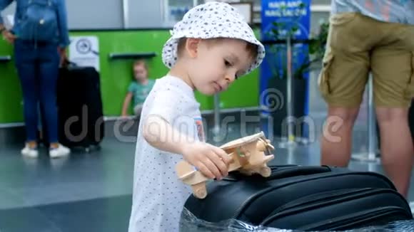 4k视频可爱的2岁幼儿男孩在国际机场候机楼玩木玩具飞机视频的预览图