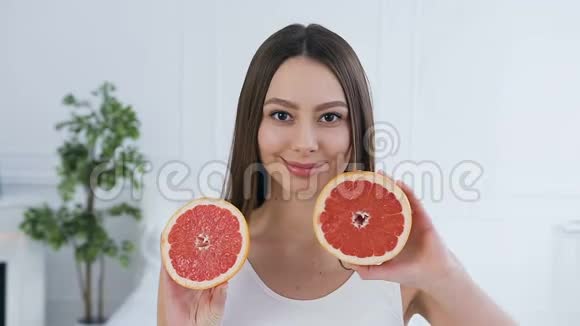 英俊的黑发女人摆着两半葡萄柚视频的预览图