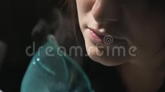 使用雾化器和吸入器进行治疗年轻女性通过吸入面罩吸入侧视图视频的预览图