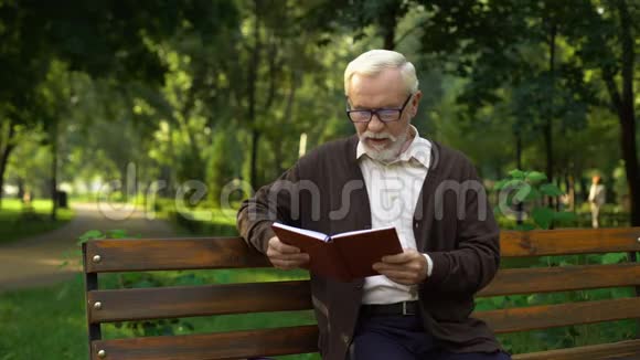 孙子和爷爷一起看书在公园里休息视频的预览图