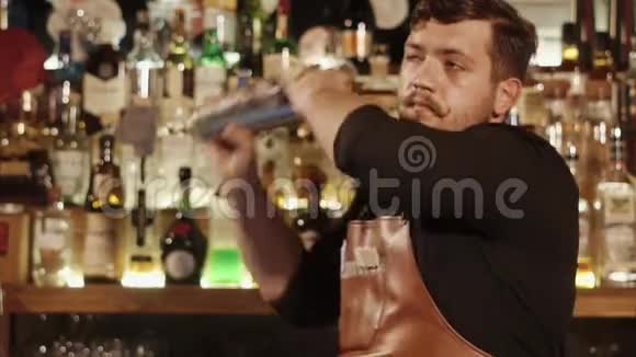 严肃的酒保留着滑稽的小胡子用鸡尾酒摇晃金属碗视频的预览图