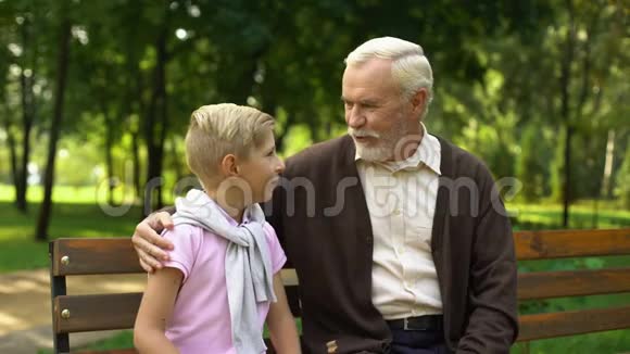 孙子和爷爷分享秘密坐在公园里信任关系视频的预览图