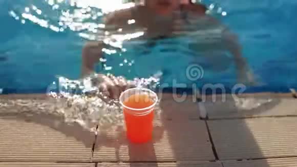 女人游泳到游泳池的边缘取新鲜的果汁喝它然后游泳离开阳光明媚的一天在游泳池里视频的预览图