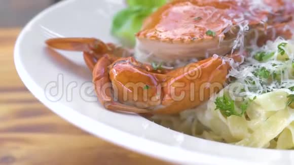 意大利海鲜面食红蟹新鲜草本调味料和奶酪放在木桌上的白色盘子里服务尺寸视频的预览图