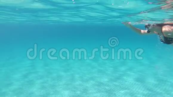 一个穿着黑色比基尼的年轻美女带着面具和浮潜在蓝色的水里游泳动作缓慢视频的预览图