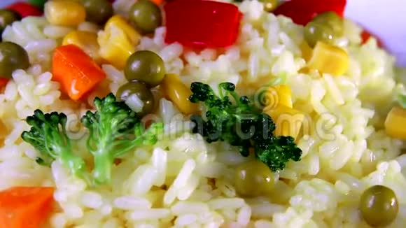 大米与蔬菜片特写绿色和红椒在一个白色的盘子旋转视频的预览图