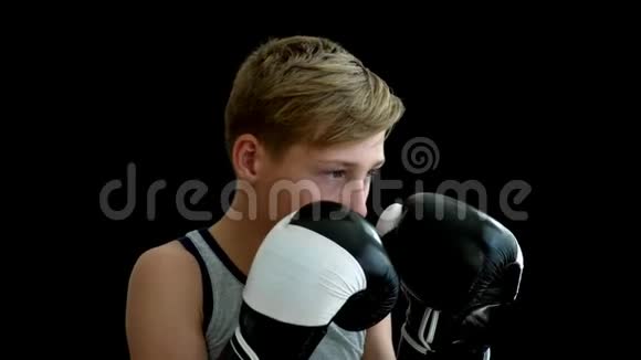 一个年轻的运动员双手戴手套他站在黑暗的背景下双手戴黑白手套视频的预览图