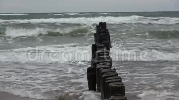 旧的废弃码头木柱码头堆在海滩和海浪上视频的预览图