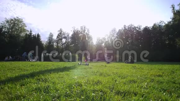 年轻迷人的女孩骑着陀螺在草地上夏日刺眼的阳光视频的预览图