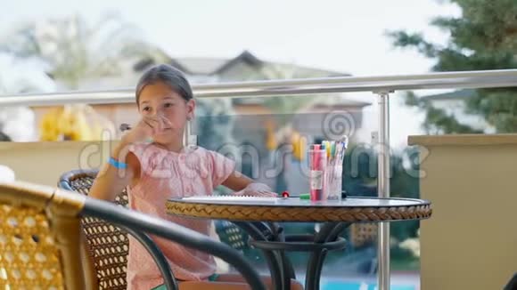 可爱的女孩坐在阳台上的桌子旁做作业视频的预览图