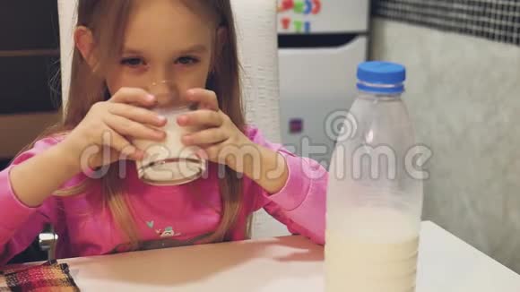 小女孩在家里的厨房里喝牛奶视频的预览图