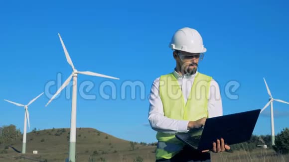 绿色能源概念一个人看他笔记本电脑上的风力涡轮机和类型4K视频的预览图