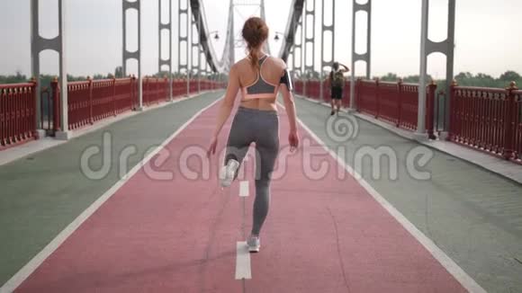 女性伸展腿和跑步的后视图视频的预览图