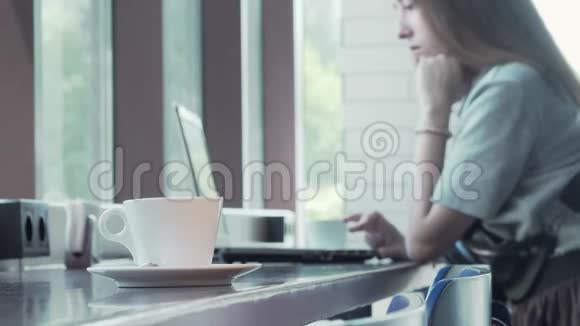 桌上的咖啡杯背景上的笔记本电脑上工作的女人视频的预览图