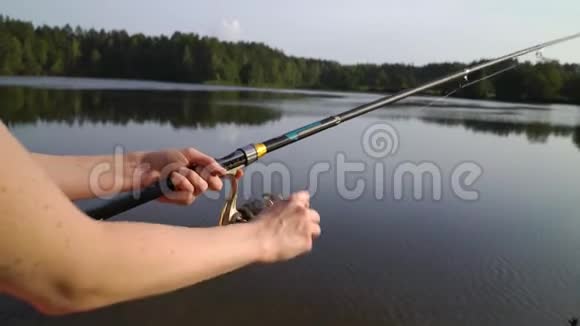 女双手握鱼竿扭住线圈渔夫拿着一根纺棒在河湖池塘里钓鱼视频的预览图
