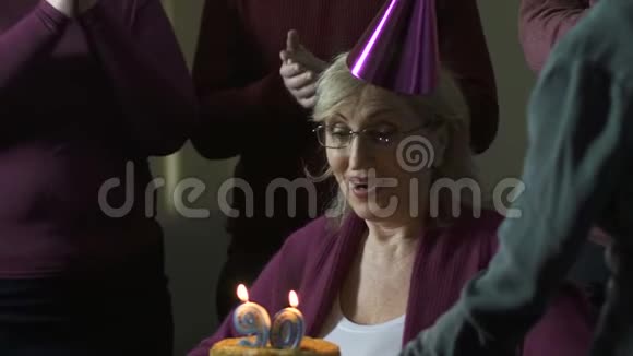 快乐的女人在蛋糕上吹蜡烛许愿90岁生日玩得开心视频的预览图