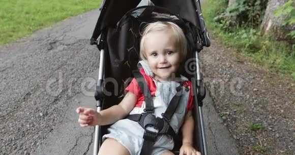 夏天快乐的小女孩坐在婴儿车里视频的预览图