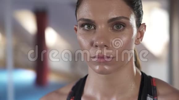 在一次剧烈的锻炼后凝视着相机一位美丽的女运动员的脸特写视频的预览图
