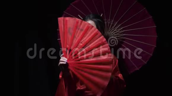 可爱的东方女士微笑着展开红色的扇子然后用它遮住一半的脸视频的预览图