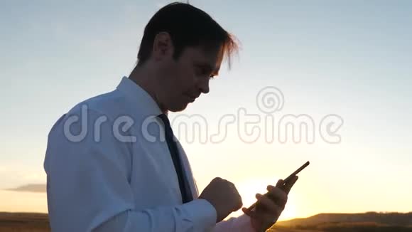 日落时分公园里一个戴着平板电脑的人商人在智能手机上对着天空说话移动电话视频的预览图