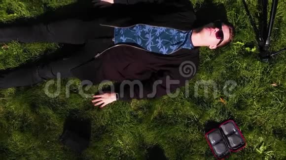 躺在草地上的人被一个三脚架闪光和背包包围着视频的预览图