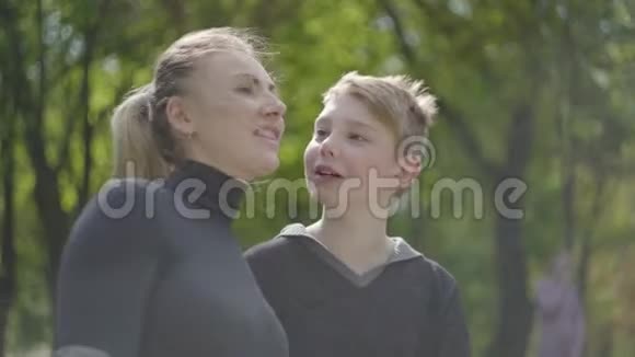 肖像年轻的母亲和她十几岁的儿子一起在公园里休息友好的家庭户外休闲视频的预览图
