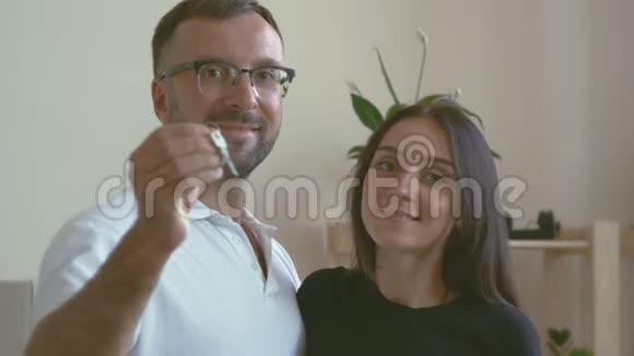 一个戴眼镜的男人和一件白色的t恤拥抱着他黑发的妻子丈夫手里拿着新车的钥匙视频的预览图