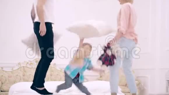 幸福一家人在床上蹦蹦跳跳扔软玩具幸福的家庭观念爸爸妈妈和小男孩一起跳视频的预览图
