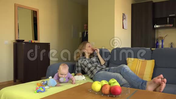 孩子保姆放松地躺在沙发上当意外地回到婴儿父亲4K视频的预览图