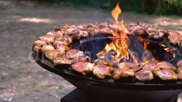 圆形烧烤架里面有明火为夏季野餐煮鸡或火鸡视频的预览图