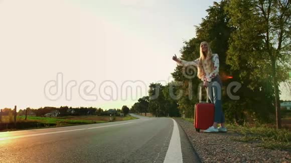 一个女旅行者走在路上疲惫的年轻女子背包客开始了一段在阳光明媚的乡村道路上的旅程视频的预览图