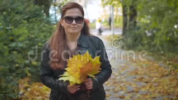戴着黄叶大太阳镜的漂亮女人在公园散步视频的预览图